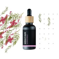 Bouteille en verre noir avec bouchon en bois contenant de l'huile essentielle BIO de poivre rose, entourée de délicates fleurs roses et de brindilles vertes