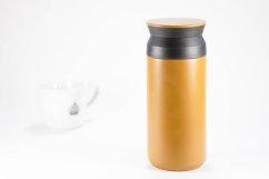 Gelbe Reisethermoskanne Kinto Travel Tumbler mit dunkelgrauem Deckel, zylindrisches Design mit matter Oberfläche auf weißem Hintergrund mit Schatten