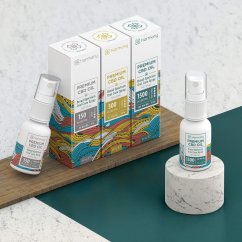 Trei cutii albe Harmony Premium CBD ulei spray în diferite intensități 150, 500 și 1500 mg cu modele colorate pe masă din lemn