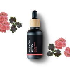 BIO Geranium roze essentiële olie in een zwarte glazen flesje met houten dop en pipet, omringd door roze geraniums