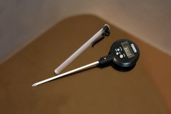 Digitální teploměr Eutech Oakton s černým plastovým tělem a dlouhou stříbrnou nerezovou trnovou sondou na béžovém podkladu