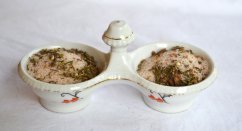 Biała porcelanowa podwójna miska ze złotą krawędzią wypełniona różową himalajską solą konopną z chili, ozdobiona zielonymi ziołami i przyprawami
