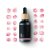 Bouteille en verre noir avec pipette en bois entourée de pétales de rose sur fond blanc - Huile essentielle bio Rose 10ml