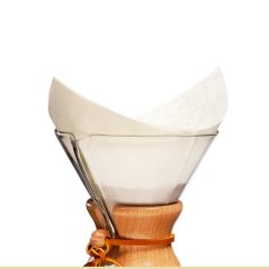 Skleněný překapávač Chemex s dřevěným límcem a koženým páskem, v něm vložený bílý papírový filtr FS-100 připravený k použití
