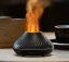 Černý aroma difuzér s barevným plamenem, oranžový realistický plamen, elegantní design s drážkovaným vzorem, vedle černé kavové šálky Černý aroma difuzér s barevným plamenem, oranžový realistický plamen, elegantní design s drážkovaným vzorem, vedle černé kavové šálky
