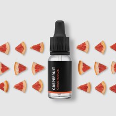 Zwarte glazen fles met pipet met grapefruit essentiële olie, omringd door kleine driehoekige plakjes rode grapefruit