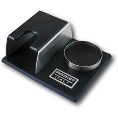 Rocket Espresso pěchovací stanice z černého materiálu s kovovou podporou pro portafilter a kulatým otvorem pro tamper na gumové podestě