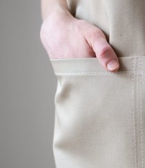 Detalle de bolsillo beige en delantal de barista con costura limpia y diseño práctico para guardar herramientas y pequeños objetos