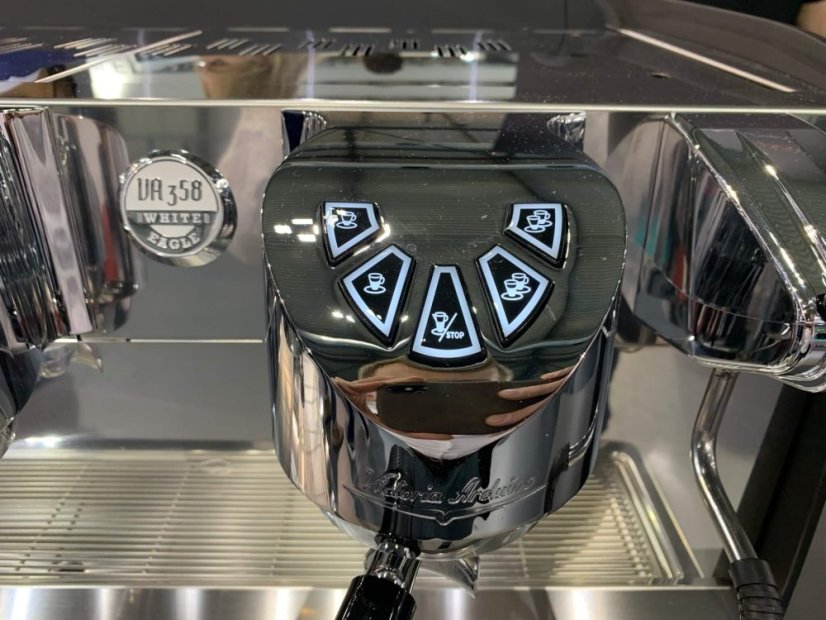 Zbližení na logo Victoria Arduino White Eagle umístěné na chromové hlavě kávovaru s precizně vyrobenými detaily a kvalitním provedením