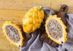 Żółty pitahaya owoc smoka przekrojony na drewnianej desce, biała miąższ z czarnymi pestkami, żółta szorstka skórka, egzotyczny owoc Żółty pitahaya owoc smoka przekrojony na drewnianej desce, biała miąższ z czarnymi pestkami, żółta szorstka skórka, egzotyczny owoc