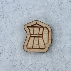 Drewniany medal Zakonu Złotego Dzbanuszka w kształcie nieregularnego kawałka drewna z wylaserowanym symbolem moka dzbanuszki na jasnym drewnianym podłożu