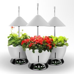 Tři bílé hydroponické systémy UrbanGreen I-Grow G601-C s LED osvětlením 40W, černými ovládacími panely a pestrou zelení s červenými květy