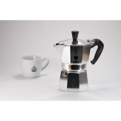 BIALETTI MOKA EXPRESS 6 kuppia - hopeinen moka-kahvipannu valkoisella logolla tummaa taustaa vasten