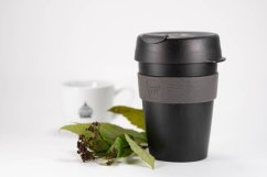 KeepCup Original Doppio M schwarz-grau Reisebecher mit Deckel, neben Teebaumblättern und weißer Porzellanteekanne
